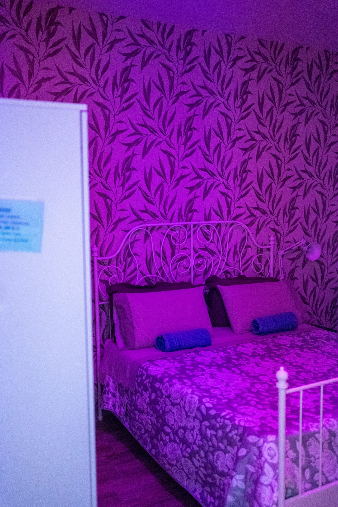 Camera con illuminazione a cromoterapia accesa in viola e carta da parati damascata