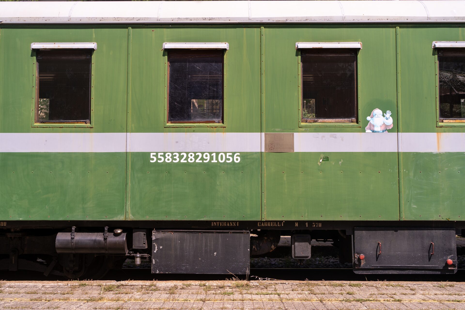 Una carrozza verde in legno del Treno della Sila ferma sul binario